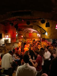 a group of people are gathered together in a cave like setting with lights on the ceiling