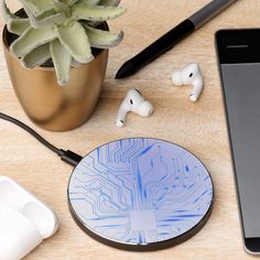 an iphone, headphones and earbuds are on a table next to a plant