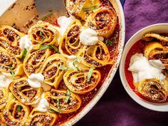 an oval casserole dish filled with pasta and cheese, next to a bowl of sour cream