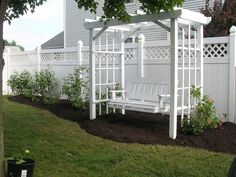 a white bench sitting in the middle of a yard next to a tree and fence