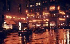 a city street at night with cars parked on the side