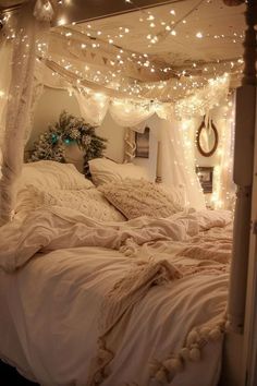 a bed with white sheets and lights on the headboard, in a room that has been decorated for christmas