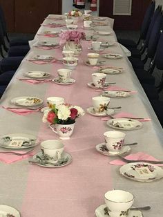 a long table is set up with tea cups and saucers for a formal dinner