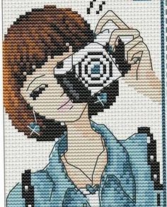 a cross stitch picture of a woman holding a camera