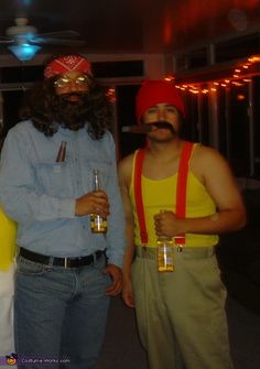 three men dressed up in costumes posing for a photo with beer glasses on their heads