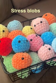 a basket filled with lots of different colored stuffed animals on top of a couch next to a pillow