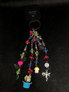 a keychain with charms attached to it on a black surface next to a cell phone