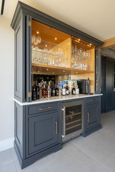 an open bar with wine glasses and bottles on the top shelf in a home kitchen