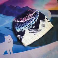 a knitted hat sitting on top of a table next to a snow covered mountain