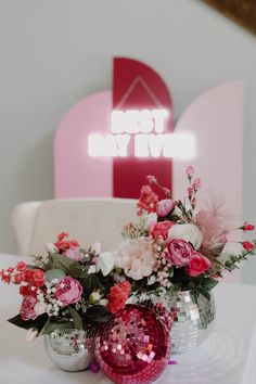 two vases filled with flowers sitting on top of a white table next to a chair