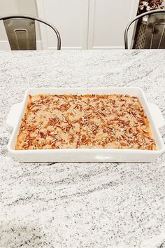 a casserole dish sitting on top of a table with chairs in the background