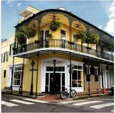 a bike parked in front of a yellow building with balconies and plants on the balcony