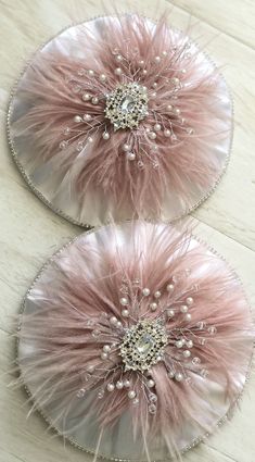 two pink and white feathers with pearls in the center on top of a wooden table