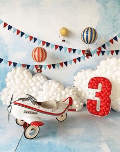 an airplane with balloons attached to it in front of a number three balloon wall decoration