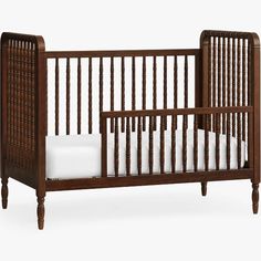 a wooden crib with white sheets in it