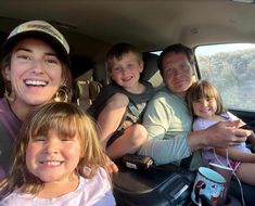 a group of people sitting in the back of a car with two children and one adult