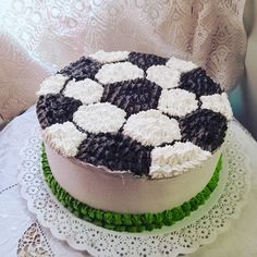 a cake with white and black icing on top of a doily covered table