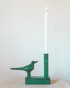 a green candle holder with a bird on it and a lit candle in the middle