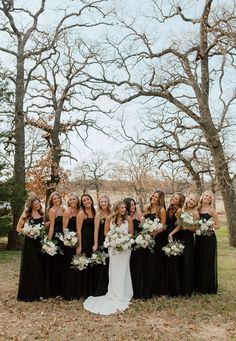 a group of women standing next to each other in front of trees