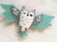 an owl ornament made out of felt sitting on top of a wooden table