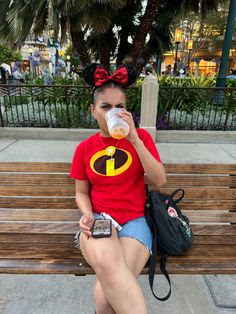 a woman sitting on a bench drinking from a cup