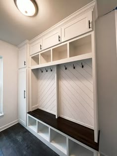 an empty room with white cabinets and benches on the wall, in front of a window