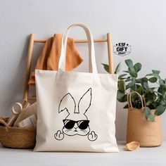 "Bunny Middle Finger Tote Bag, Bunny Lover Tote Bag, Funny Shoulder Bag, Bunny Totes, Easter Wishes Tote, Christian Totes, Bunny Lover Gift Personalized tote bags are perfect for yourself, Your Company, or as a gift! These are also the ideal bride's, Bridal Shower, Baby Shower, Birthday Party, gift, or proposal gift. IMPORTANT! Natural, White, Gold, Yellow, And Pink color totes Will be black Text color; all Other Colors Will Be White. PRODUCT *Measurements15\"L x 16\"H *12 oz./yd² (US), 20 oz (CA), 100% heavy cotton canvas *20\" canvas webbed handles * 9\" handle drop *Made from Heavy duty cotton canvas fabric *DTF printing for the best color quality * Bulk discounts are available upon request. *Put N/A In the personalization Box For  Blank Tote Bag  Check the Tote bag Color And Text Color Casual Bucket Bag As Gift, Casual Bucket Bag For Gift, Trendy Large Capacity Bags For Gifts, Casual Shoulder Bag As Gift, White Shoulder Beach Bag As Gift, Trendy Pouch Shoulder Bag As Gift, Rectangular Casual Bags For Gift, Casual Rectangular Bag For Gifts, Trendy Shoulder Bag Gift