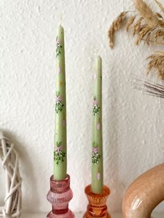 two green candles sitting on top of a table