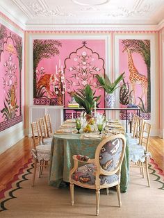 a dining room decorated in pink and green with giraffes on the wall