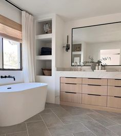 a bathroom with a tub, sink and large mirror on the wall next to it