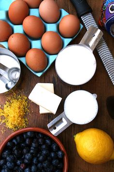 an assortment of ingredients for making blueberry muffins on a wooden table top