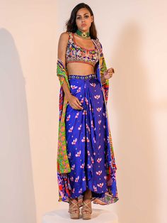 A three-piece Blue Indica Mirror Dhoti Skirt Set Paired with Bralette and Cape from the Juhi Bengani collection – Rang-Festive 2022. This gorgeous blue indica silk mirror dhoti skirt is paired with a heavy embroidered multicolored bralette blouse. The bright and vibrant colors with floral print, heavy embroidery of mirror, beads, stones, and thread sequence work enhance this satin dhoti skirt set. The indica blue dhoti skirt has a side opening at the waistline. This outfit is completed with a mu Skirt Length, Bralette, Lehenga, Custom Sizing, Two Piece Skirt Set, Comfort Fit, Womens Sizes, Satin, Floral Prints