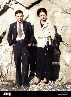 two men standing next to each other in front of a rock wall - stock image