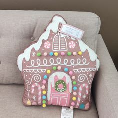 a pink and white gingerbread house pillow on a gray couch with a price tag