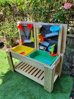 a child's sand and water table in the grass with toys on it,