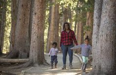 a woman and two children are walking through the woods