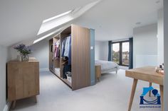 an attic bedroom with white carpeting and skylights above the bed, closet doors open to let in plenty of light