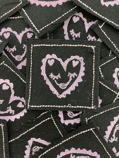 a pile of black and white patches with pink hearts on them