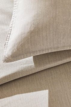 two pillows are laying next to each other on a bed sheet with brown and white stripes