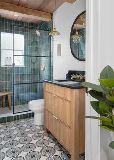 a bathroom with green tile and wood accents