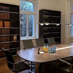 an empty conference room with bookshelves in the background and several chairs around it