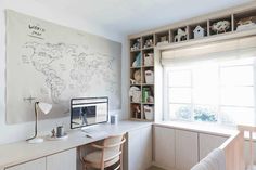 a desk with a computer on top of it in front of a wall mounted map