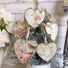 four heart shaped ornaments sitting on top of a table next to a vase with flowers