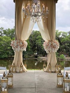 an outdoor wedding ceremony setup with chandelier and flowers on the aisle, overlooking a pond