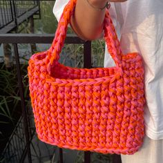 a woman holding a pink and orange purse