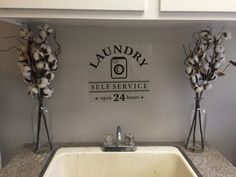 two vases with cotton in them are next to a sink that has the words laundry self service on it