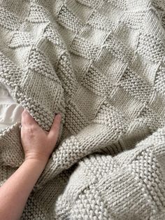 a person is laying in bed with a blanket on top of them and their hand resting on the edge of the blanket