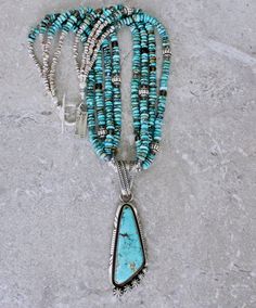 This eye-catching Necklace showcases a Kingman Turquoise and Sterling Silver Pendant by Navajo Jewelry Artist Nila Cook Johnson. Johnson is known for the exceptional quality of her work, and this piece is no exception. The triangular Pendant features a soft blue Kingman Turquoise stone, splashed with filaments of brown matrix. The stone is wrapped in a Sterling Silver Bezel and encircled by twisted Sterling Silver Wire, which has been oxidized for contrast. It sits on Sterling Silver Plate that Artisan Multi-stone Turquoise Necklace, Artisan Blue Multi-stone Turquoise Necklace, Artisan Blue Turquoise Multi-stone Necklace, Bohemian Blue Multi-stone Turquoise Necklace, Blue Multi-stone Bohemian Turquoise Necklace, Blue Multi-stone Turquoise Necklace For Jewelry Making, Blue Multi-stone Round Beads Jewelry, Turquoise Multi-stone Beaded Necklaces With Round Beads, Johnson Johnson