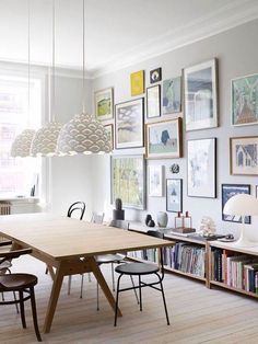 a dining room table with chairs and pictures on the wall behind it in front of a bookshelf