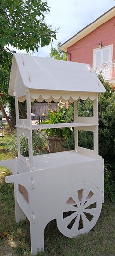 a white cart sitting in the grass next to a house